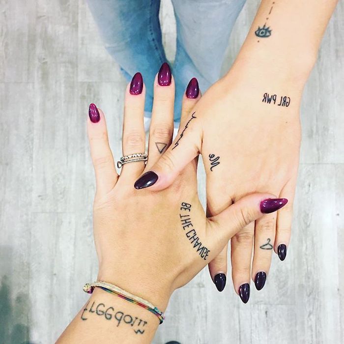Le mani di due donne con tatuaggi scritte e disegni simbolici 