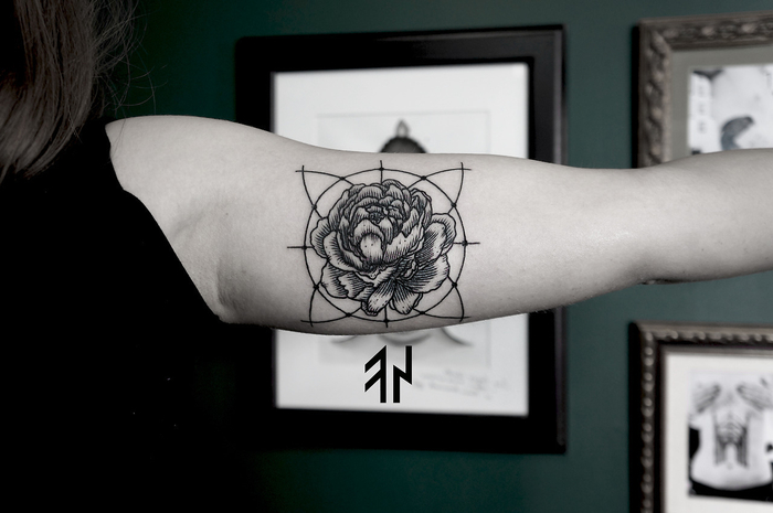 Tatuaggio geometrico sul braccio di una donna con fiore dentro un cerchio 