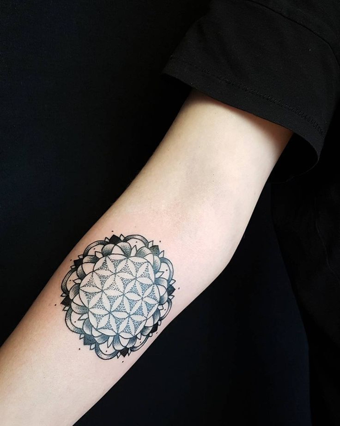 Tatuaggi geometrici e un disegno con cerchi e petali di fiori sul braccio di una ragazza