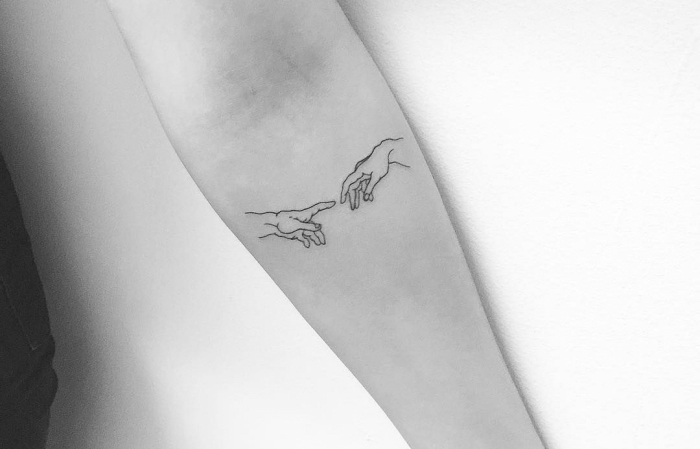 Tatuaggi piccoli e un'idea con il disegno di due mani sul braccio di una donna