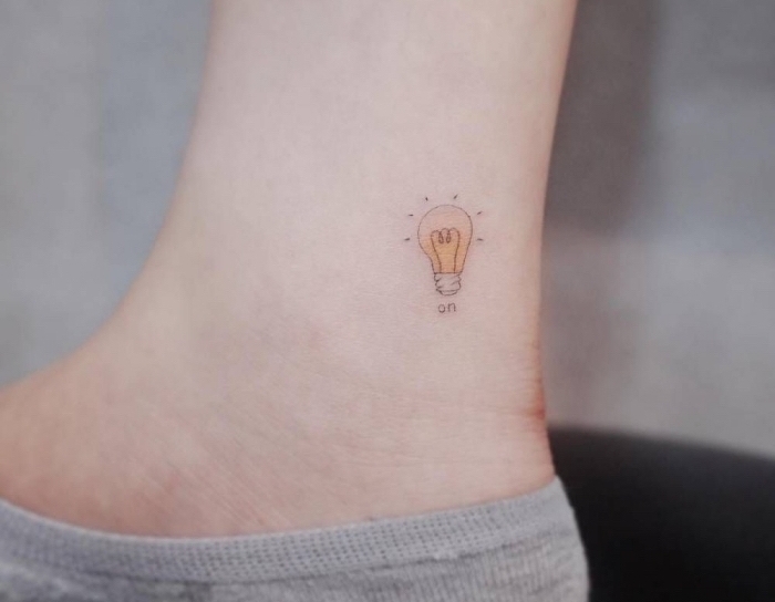 Piccoli tatuaggi femminili, tattoo colorato sulla caviglia di una donna con i disegno di una lampadina