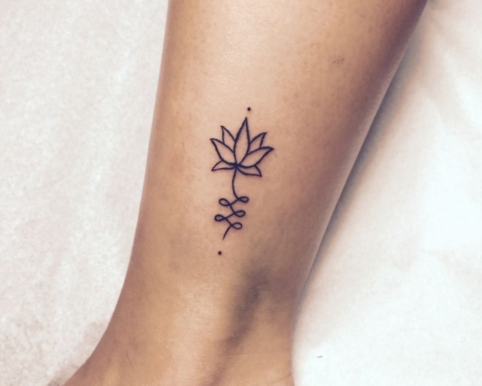 Tatuaggi simboli e un piccolo tattoo di fiore di loto sulla caviglia di una donna