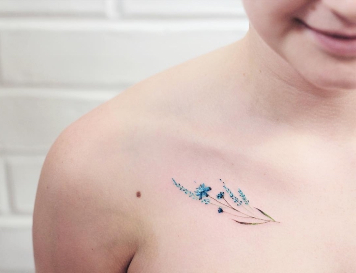 Idee tatuaggi piccoli particolari femminili e una proposta con un fiore di colore blu sulla clavicola 