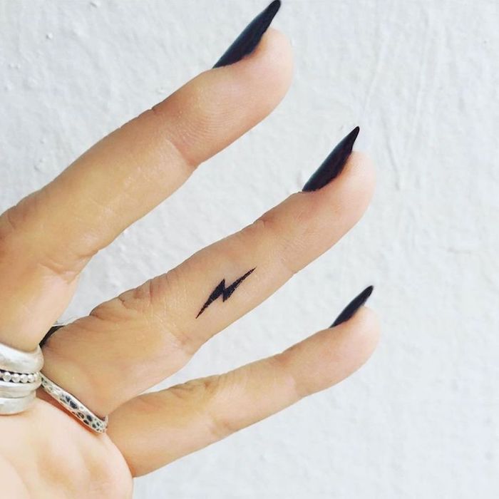 Mani tatuate e un'idea con un piccolo fulmine sul dito anulare di una donna