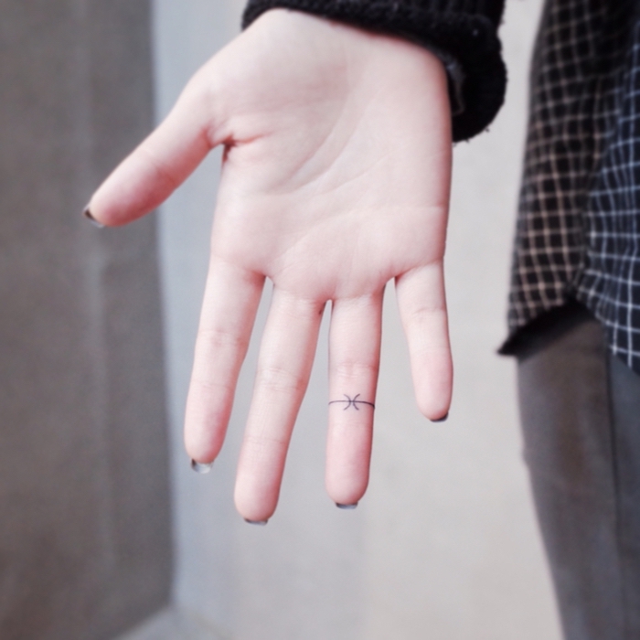 Idea per dei tatuaggi discreti e una proposta con un disegno sul dito anulare di una donna