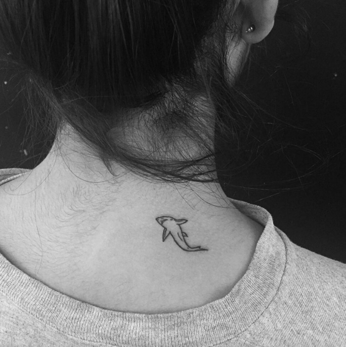 Il tattoo di uno squalo sulla schiena di una donna con maglione grigio