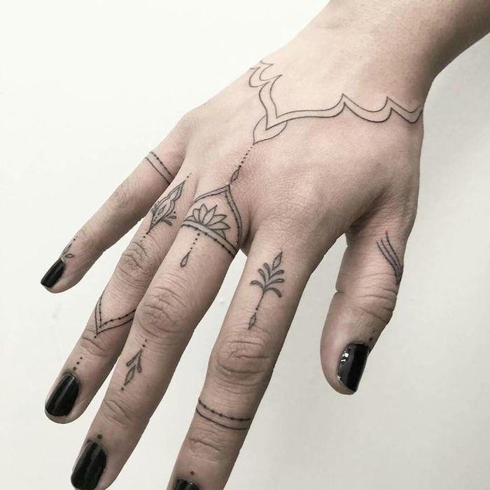 La mano di una donna tatuata con fiore di loto e simboli mandala