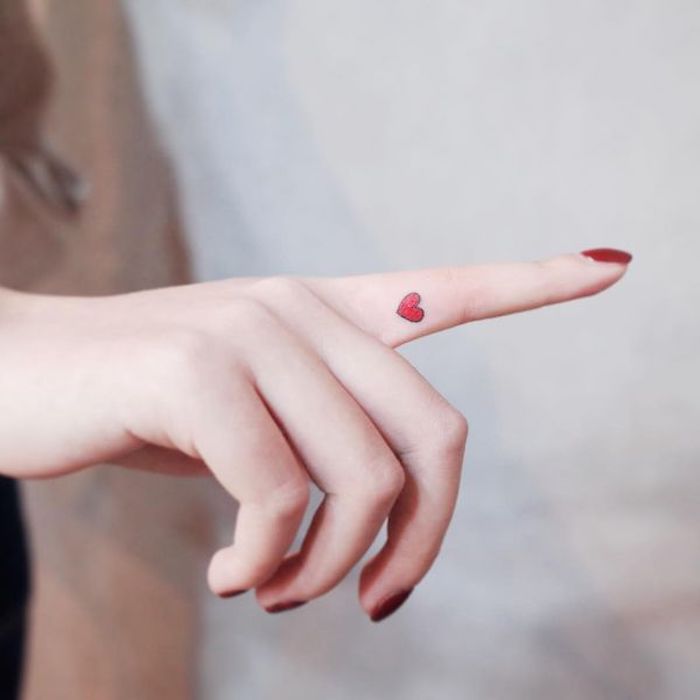 Un piccolo cuore di colore rosso sull'indice della mano di una donna