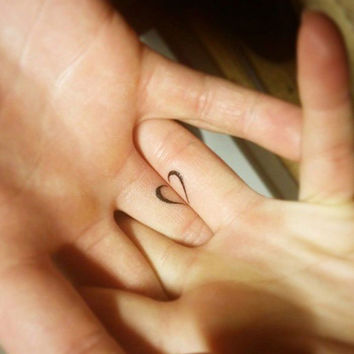 Mani tatuate e un'idea con tatuaggio di coppia con un cuore a metà sulle dita
