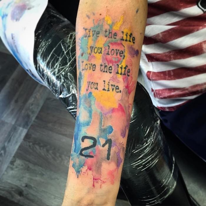 L'avambraccio di una donna con tattoo colorato e scritta con numero 21