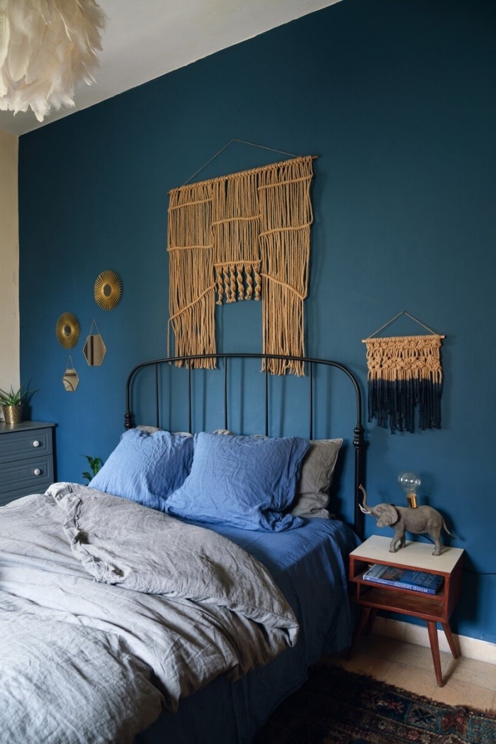 Una camera da letto con parete di colore blu e creazioni macramè con corda canapa 