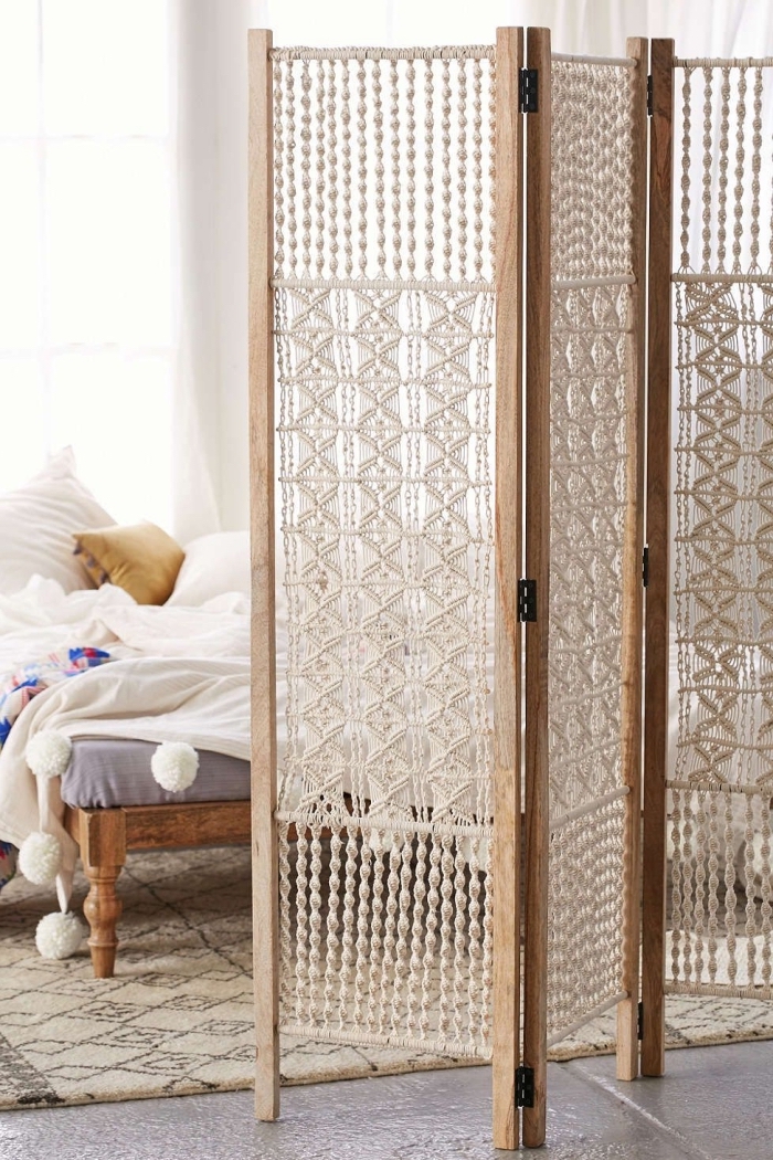 Separè di legno con tenda di macramè con intrecci, camera da letto con un tappeto etnico