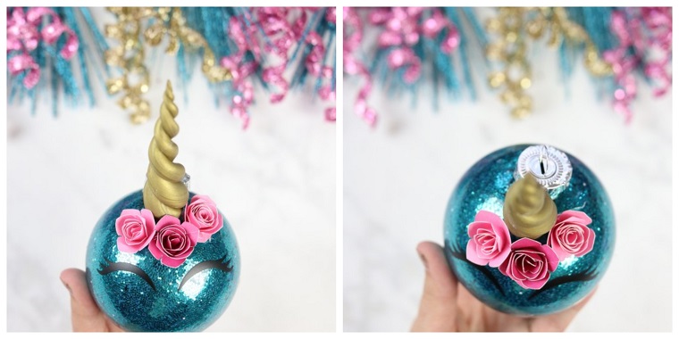 Decorazioni natalizie fai da te tutorial, una pallina di colore blu con fiorellini rosa e corno di pongo