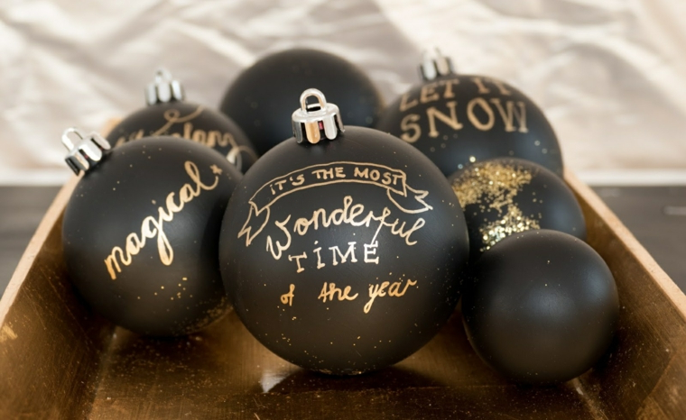 Palline di Natale fai da te di colore nero e scritte con pennarello indelebile oro