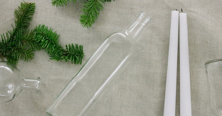 Lavoretti creativi Natale, una bottiglia di vetro con candele e rami verdi dell'albero natalizio 