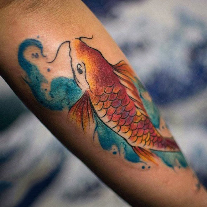 Tatuaggi piccoli significativi con il disegno di un pesce colorato sull'avambraccio di un uomo