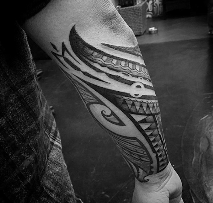 Il braccio di un uomo con un tattoo di simboli maori 