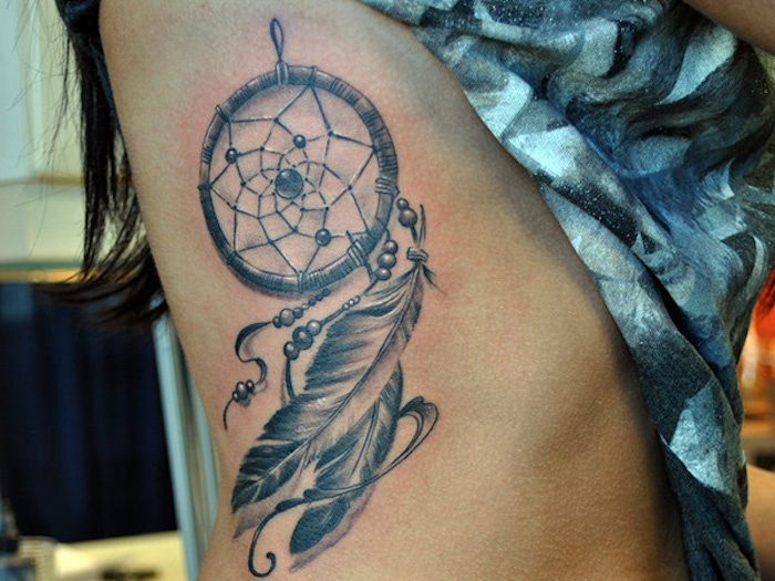 Tatuaggio acchiappasogni sulla pancia di una donna con piume e perle