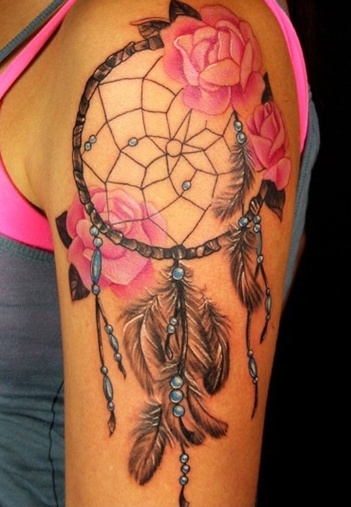 Tatuaggio acchiappasogni con rose e piume sulla spalla di una donna