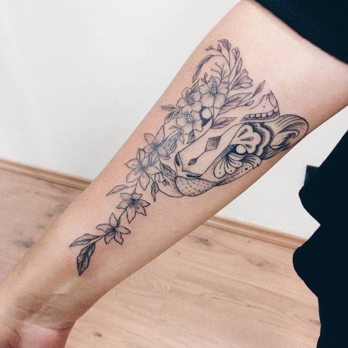 L'avambraccio di una donna con un tatuaggio con fiori e leggere sfumature