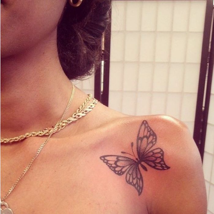 La spalla di una donna con un tatuaggio di farfalla colorata 