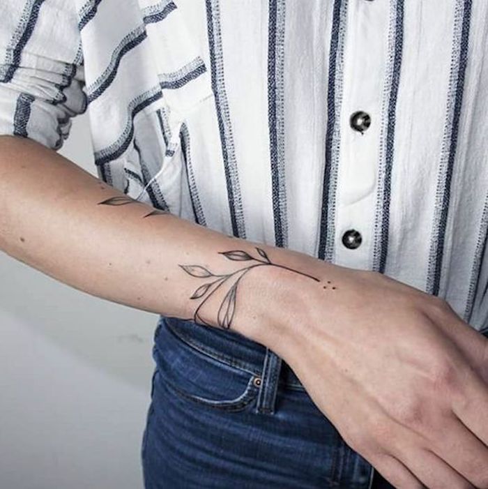 Tatuaggio floreale sul braccio di una donna, ragazza con jeans e camicia 