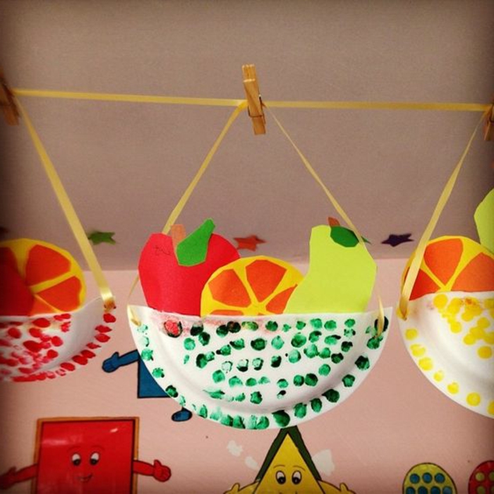 Una decorazione sospesa con frutta finta di carta e una ciotola di piatto di carta colorato