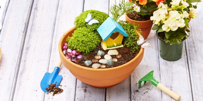Vaso di terracotta come un giardino in miniatura con erba e casetta di legno