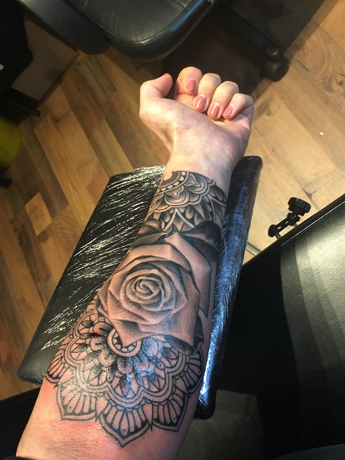 Tatuaggio braccio dinne con fiori e simboli mandala con sfumature