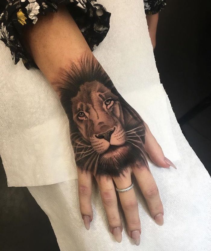 Tattoo disegno animale sulla mano di una donna, anello in oro bianco sul dito medio