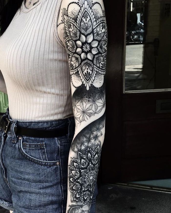 Una donna con il braccio interamente tatuato con motivi mandala
