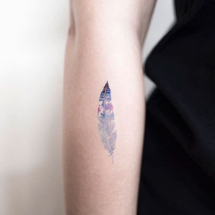 Una piuma colorata come un tattoo temporaneo sull'avambraccio di una donna