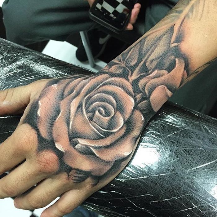 La mano di una donna con un tattoo di rosa con leggere sfumature sul polso