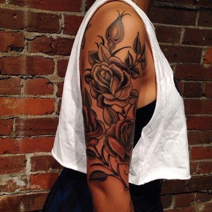 Il braccio di una donna tatuato con motivi floreali con leggere sfumature di colore rosso