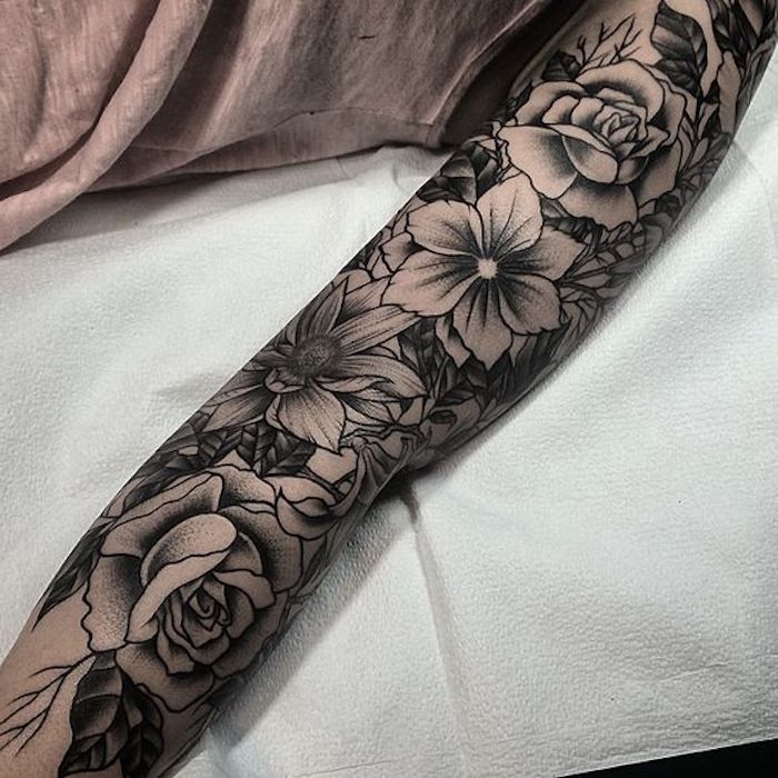 Il braccio di una donna tatuato con motivi floreali di rose e fiore di giglio