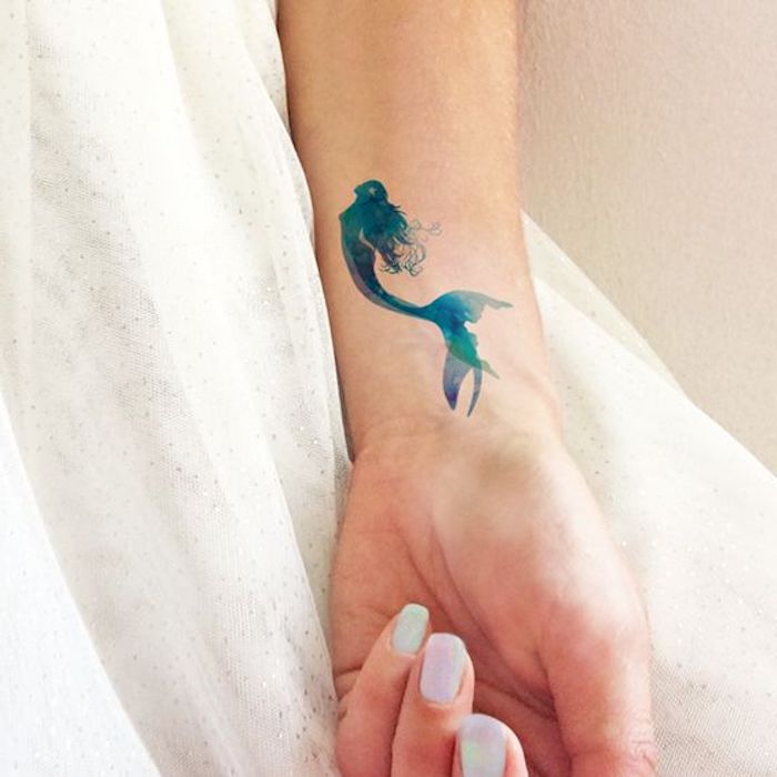 Tatuaggio temporaneo sul braccio di una donna con disegno colorato di una sirena
