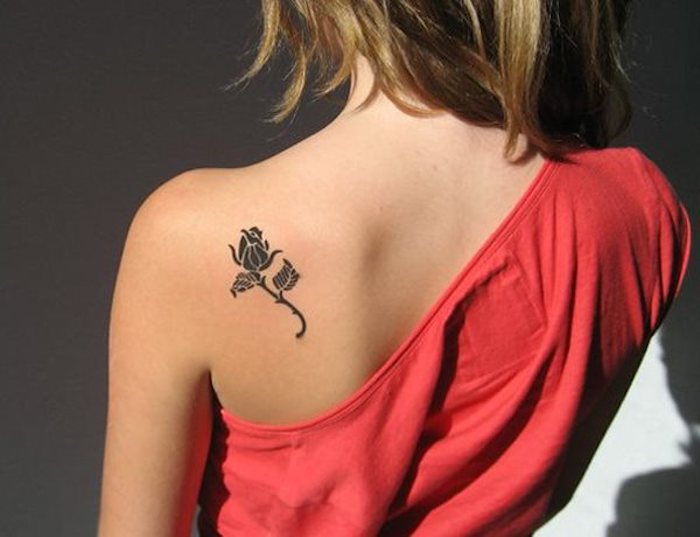 Tatuaggio di una rosa nera sulla schiena di una donna con i capelli biondi