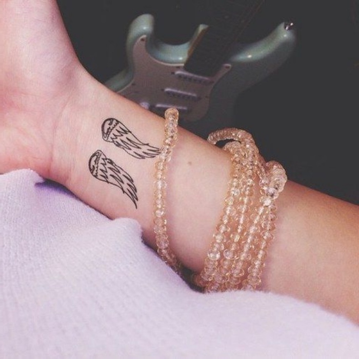 Tatuaggi sul polso, disegno ali di angelo, donna con braccialetti