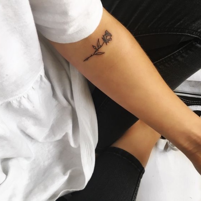 Tatuaggi avambraccio, disegno rosa sul braccio, donna con jeans neri