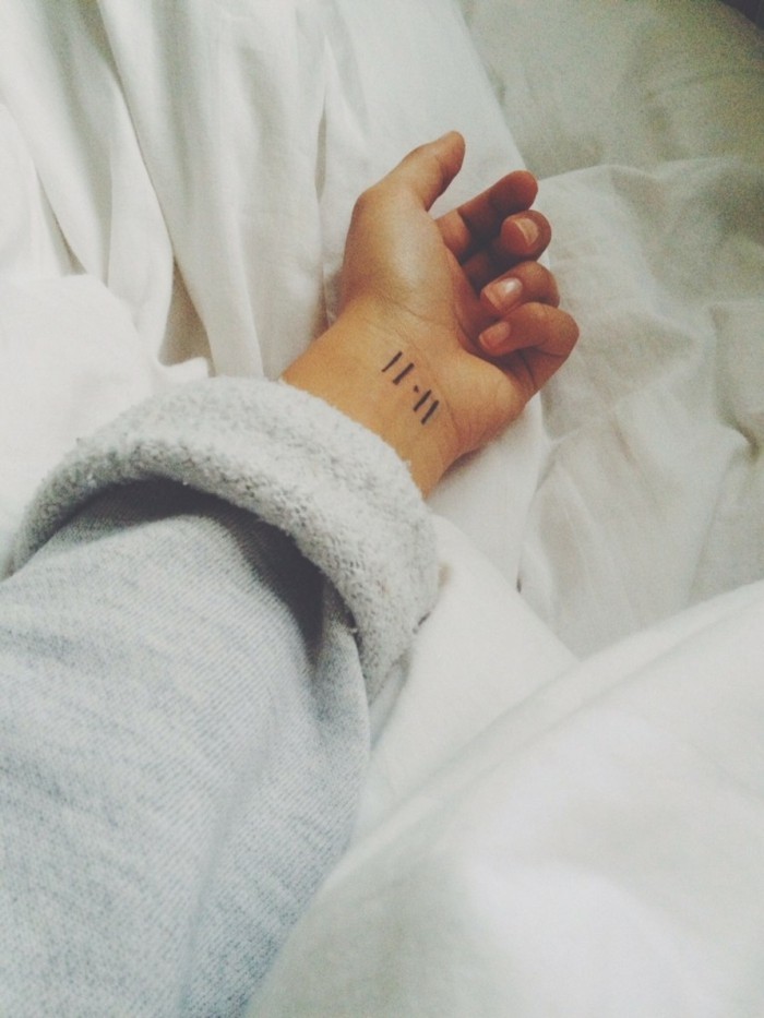 Tatuaggio polso simbolico, tattoo donna con linee, ragazza con un maglione grigio