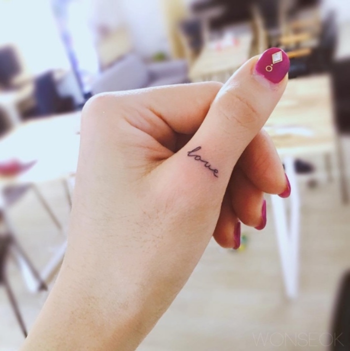 Scritta love in inglese, tatuaggio sul dito, manicure con brillantini