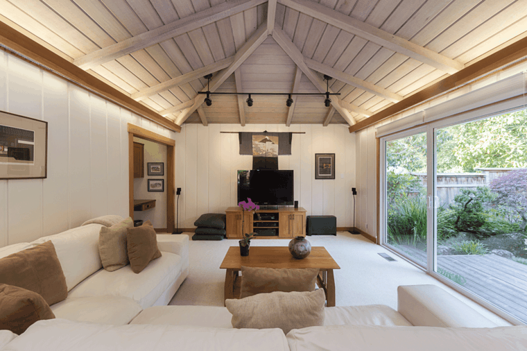 Mansarda con soffitto di legno, divano bianco angolare, tavolino bassi di legno
