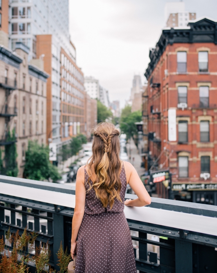 Donna su un ponte, palazzi di una città, acconciature belle, capelli di colore biondo