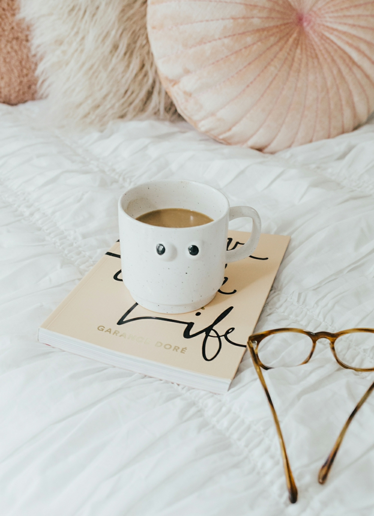 Immagini con frasi significative, tazza di caffè latte, libro e occhiali da vista