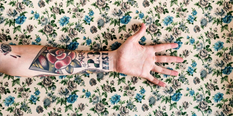 Cuore sacro tattoo, avambraccio uomo tatuato, disegno fiore rosso, scritta sul polso