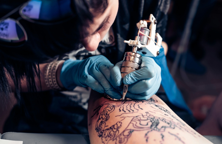 Uomo che fa un tatuaggio, pistola per tattoo, braccio uomo tatuato