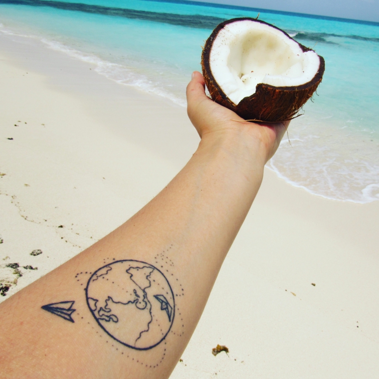 Tatuaggi più belli, tatuaggio sull'avambraccio, cocco tagliato a metà, spiaggia con acqua azzurra