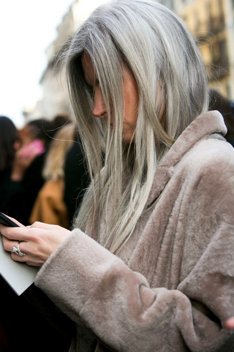 Donna che guarda il telefono, acconciatura capelli lunghi lisci, schiariture capelli