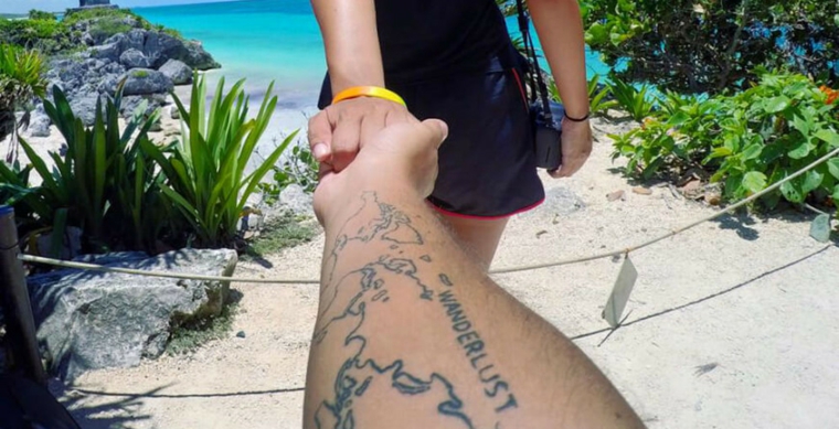 Uomo con braccio tatuato, scritta tattoo Wanderlust, tatuaggi fighi