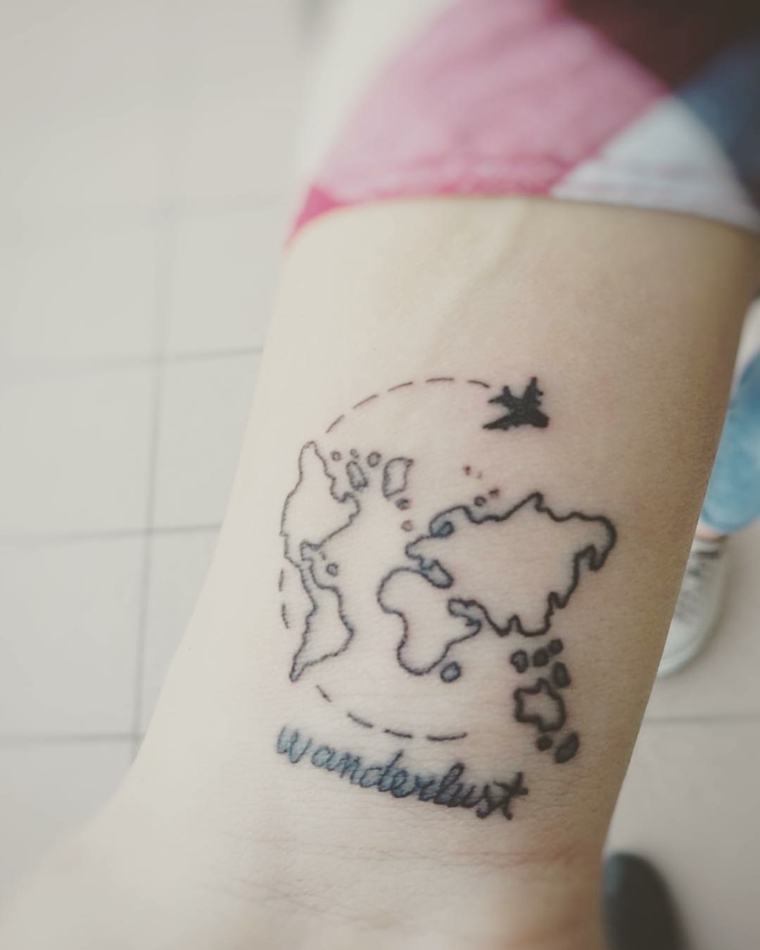 Mappamondo tattoo, tatuaggio con scritta Wanderlust, disegno continenti con aereo